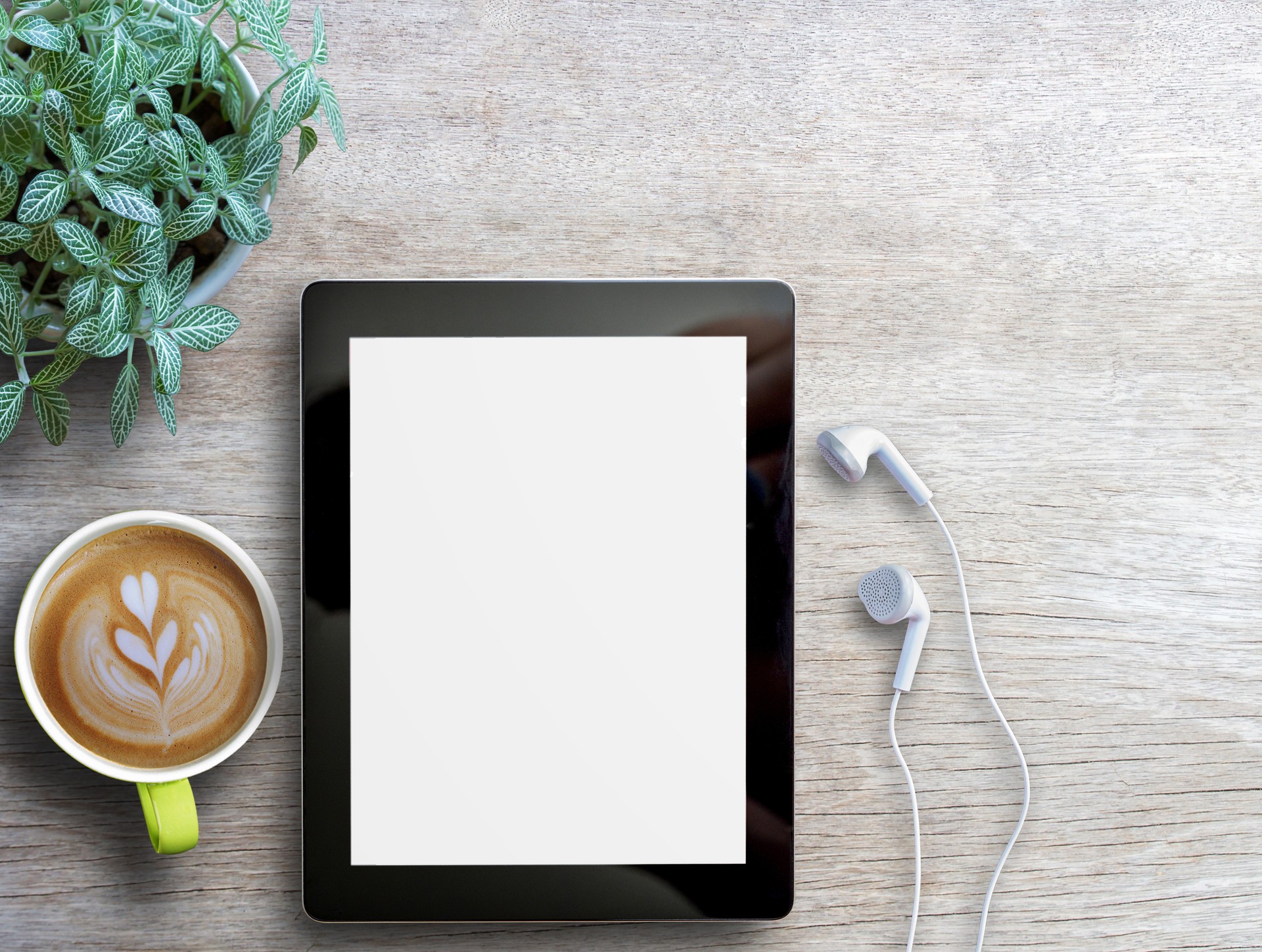 Tablet,earphone and cup of coffee with flower on wood table background.